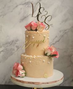 a three tiered wedding cake with pink roses on top and the initials v and s