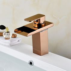 a gold faucet sitting on top of a bath tub next to a white towel