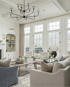 a living room with couches, chairs and a chandelier hanging from the ceiling