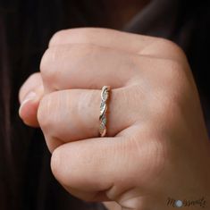 a woman's hand holding a gold and diamond ring