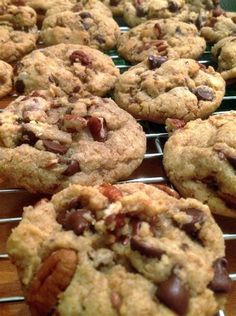 chocolate chip cookies with pecans and nuts are cooling on a rack in a bakery