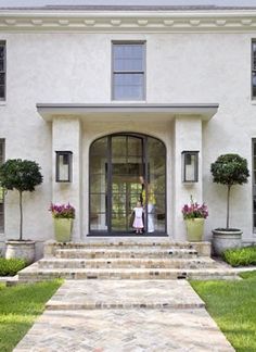 a white house with steps leading to the front door and two women standing in the doorway