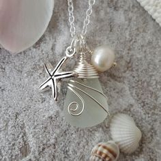 a sea glass and starfish charm on a silver plated chain next to seashells