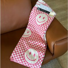 a red and white checkered tie sitting on top of a brown leather chair next to a pillow