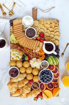 a platter filled with fruit, crackers and other snacks on a marble table