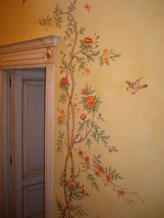 a painted wall with flowers and birds on it, next to an open closet door