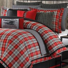 a red and black plaid comforter set with deer head on the pillow, in front of a wooden paneled wall