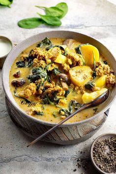 a bowl filled with food next to two spoons