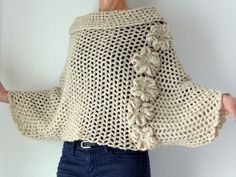 a woman is wearing a crocheted sweater and jeans