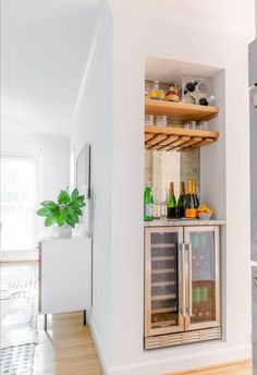 an open refrigerator in a kitchen next to a counter with bottles and glasses on it