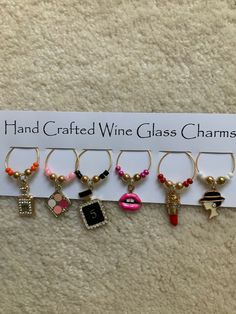 six wine glass charms are displayed on a white sign that says hand crafted wine glass charms