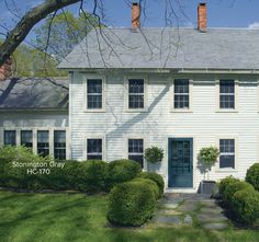 the front of a white house with blue door and windows on it's side