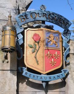 a sign that says be our guest restaurant with a rose on it's shield