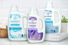 three bottles of honest liquid sitting on top of a counter next to towels and a basket