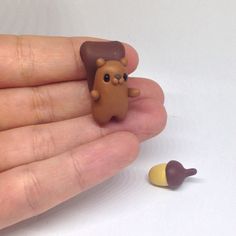 a hand holding a tiny toy animal next to an ear shaped object with a banana on it