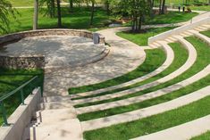 an outdoor seating area with stone steps and green grass on the ground, surrounded by trees