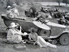 an old black and white photo of people sitting in front of a boat with umbrellas