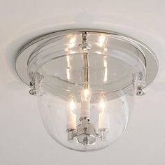 a clear glass light fixture with three candles