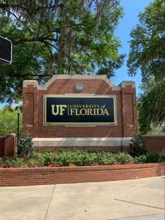 the university of florida sign is located in front of a brick building with trees and bushes around it