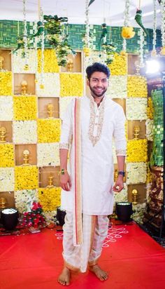 a man standing in front of a wall with flowers on it and decorations hanging from the ceiling