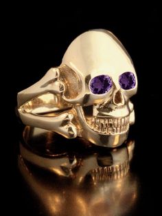 "Any pirate or nobleman would be proud to wear this completely solid 14k gold and beautifully detailed Skull and Cross Bone Ring. The skull is 1 1/8\" in length and the the substantial band is formed by a pair of crossbones. It is pictured here with both Amethyst and Ruby gem options set in the eyes. Please select your desired gemstone in the dropdown options menu. It is available with Amethyst, Peridot, or Mozambique Garnet, or for an additional price, Rhodolite Garnet, Rainbow Moonstone, Mexic Gold Skull Ring Collectible, Gold Skull Shaped Collectible Ring, Ring With Gemstone, Skull And Cross Bones, Bone Ring, Fish Jewelry, Cross Bones, Horse Necklace, Gold Skull