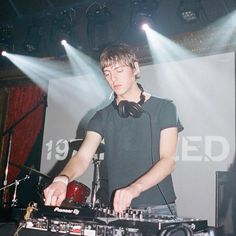 a man that is standing in front of a dj's set up with headphones on