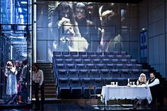 two people sitting at a table in front of a large screen with dogs on it