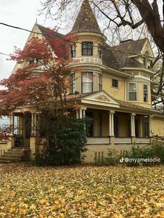 a large yellow house sitting on top of a leaf covered field