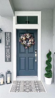 a blue front door with a wreath on it and two lanterns hanging from the side