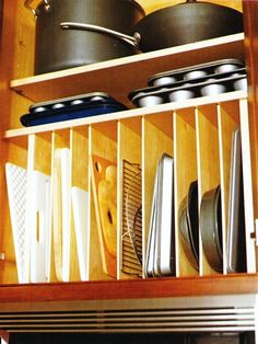 an open cabinet with pots and pans on the bottom shelf in front of it