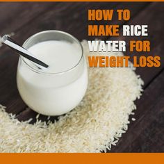 a glass filled with rice sitting on top of a wooden table next to a spoon