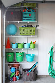 an organized garage storage area with baskets, buckets and other items on shelving