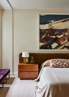 a bed sitting next to a painting on the wall in a room with white walls