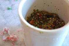 a white cup filled with lots of food on top of a table next to confetti sprinkles