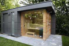 an outdoor sauna with a wooden bench and glass doors on the outside, surrounded by trees