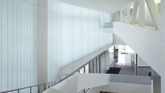 the interior of a modern building with white walls and stairs leading up to an upper floor