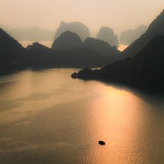 a small boat floating on top of a large body of water next to some mountains