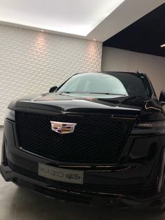 the front end of a black cadillac parked in a garage