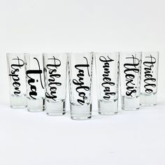 six shot glasses with black lettering on them