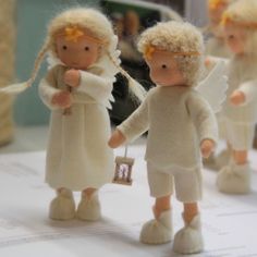 two little angels holding hands on top of a white table with other small figurines