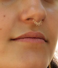 a close up of a person with a nose ring on their nose and an ear chain attached to her nose