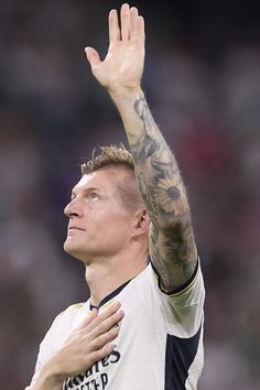 a man with his hand up in the air while wearing a white and black shirt