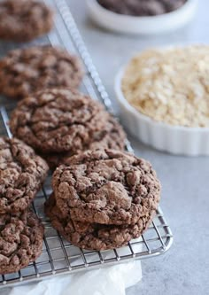 cookies cooling on a wire rack next to bowls of oatmeal