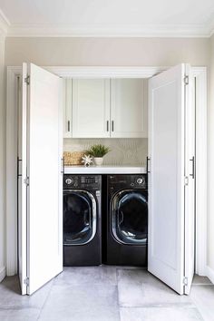 a washer and dryer in a small room with white cupboards on either side