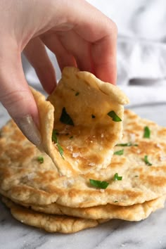 a person is holding a tortilla chip over the top of some flatbreads