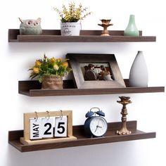 two shelves with pictures, flowers and an alarm clock on them are displaying the time