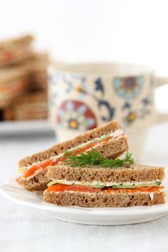 a sandwich cut in half sitting on top of a white plate next to a cup