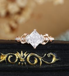 an engagement ring with a princess cut diamond in the center and gold filigrees