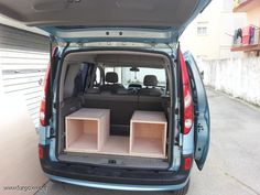 the back end of a blue van with its trunk open and two empty boxes in it