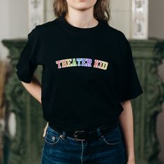 You love theater. I love theater. Why be embarrassed about the Theater Kid of it all? This colorful rainbow (perhaps even Pride-inspired!) theatre t shirt is perfect for everyone who's not afraid to talk about Wicked, Hamilton, or Dear Evan Hansen for hours. Wear to your next Broadway show or to see a musical on tour! .: 100% cotton (fiber content may vary for different colors) .: Medium fabric (5.3 oz/yd² (180 g/m .: Classic fit .: Tear-away label .: Runs true to size Cotton T-shirt With Rainbow Print For Pride, Cotton Slogan T-shirt For Pride, Pre-shrunk Cotton Rainbow T-shirt, Cotton Pride Slogan Tops, Pride Slogan Cotton Tops, Cotton Slogan Tops For Pride Festival, Cotton Slogan Tops For Pride, Rainbow Cotton T-shirt, Pre-shrunk, Rainbow Cotton T-shirt Pre-shrunk